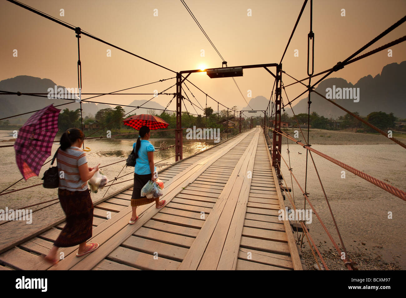 women crossing the bridge over the Nam Song River at Vang Vieng, Laos Stock Photo