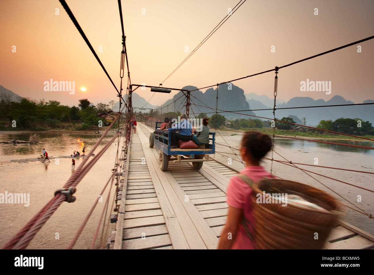 a woman and a tractor crossing the bridge over the Nam Song River at Vang Vieng, Laos Stock Photo