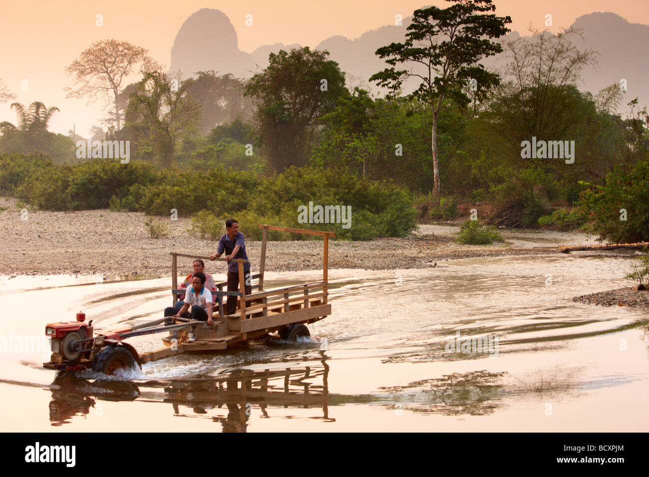 a Lao tractor wading a river at dawn nr Vang Vieng, Laos Stock Photo