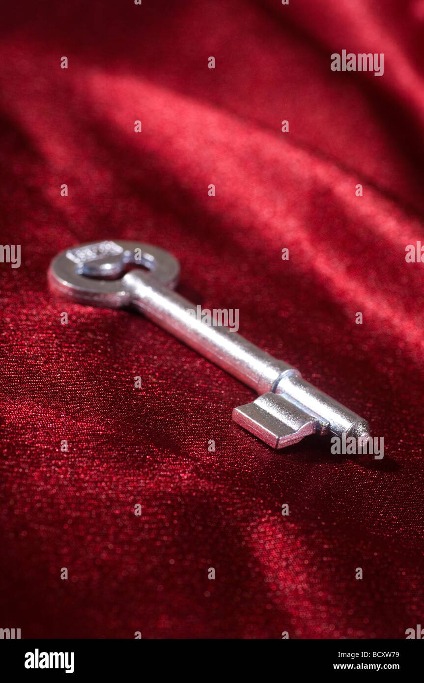 Metal key on red silk fabric Stock Photo