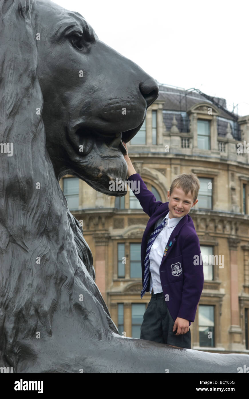 Boy by lions at Trafalgar Square, London Stock Photo