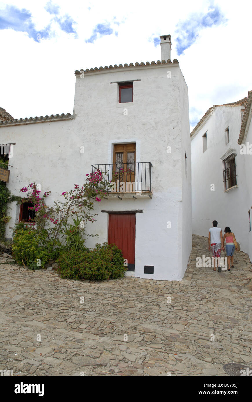 2 tourists walking up cobbled lane in village of Castillo de la Frontera, Cadiz, Andalucia, Spain Stock Photo