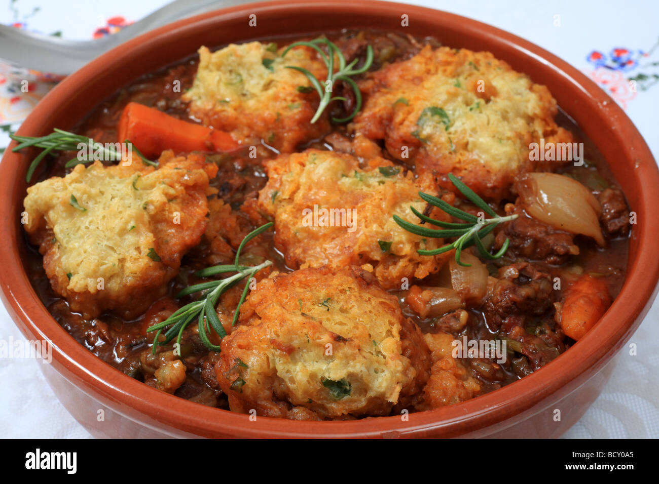 A traditional British stew topped with parsley dumplings and garnished with rosemary Stock Photo