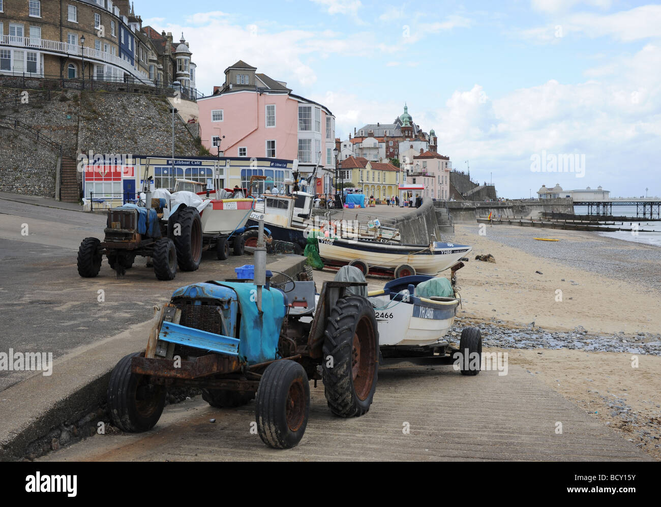 Battered old tractors pull the fishing boats up the beach at the seaside resort of Cromer on the North Norfolk coast UK Stock Photo