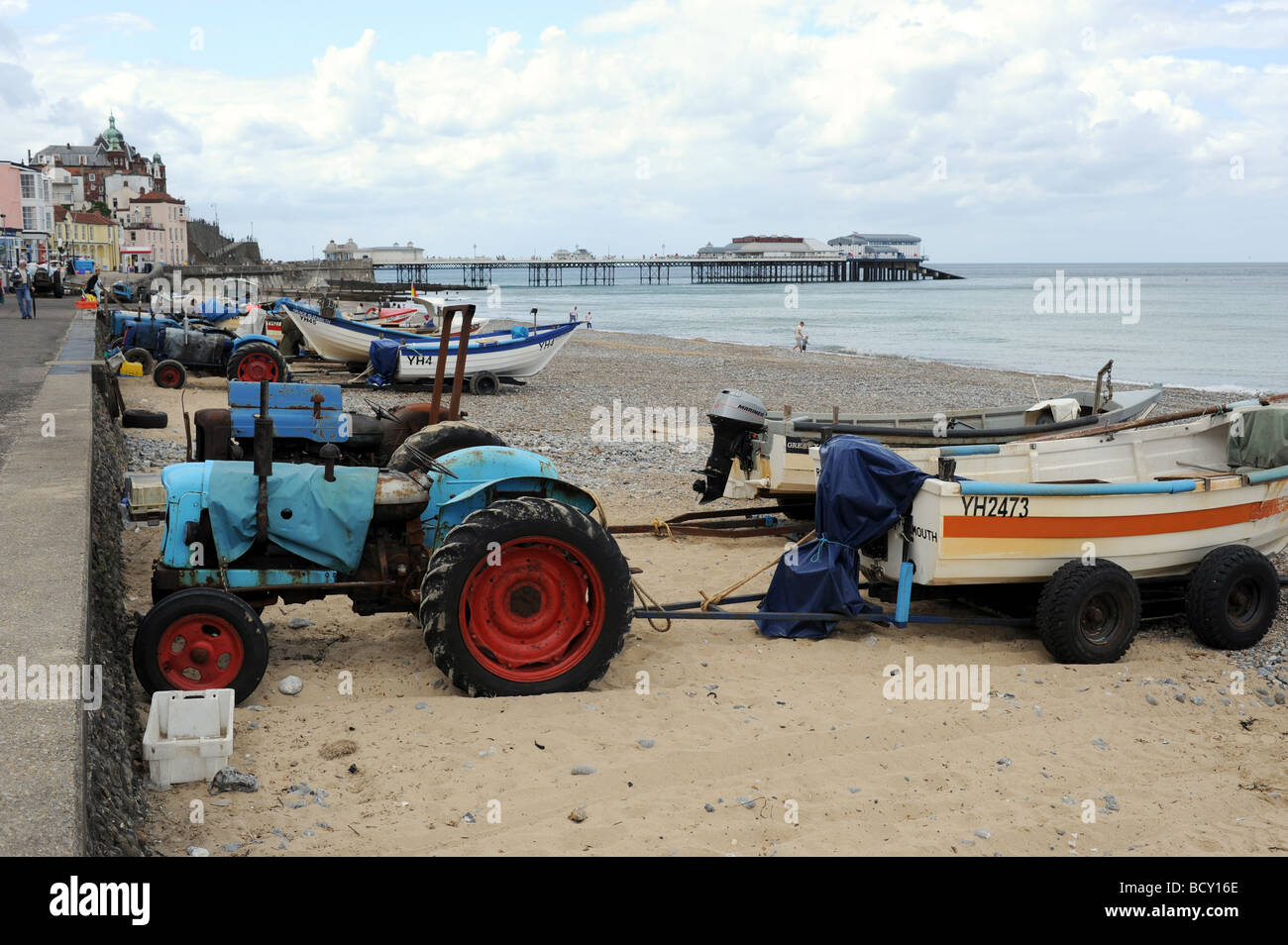 Battered old tractors pull the fishing boats up the beach at the seaside resort of Cromer on the North Norfolk coast UK Stock Photo