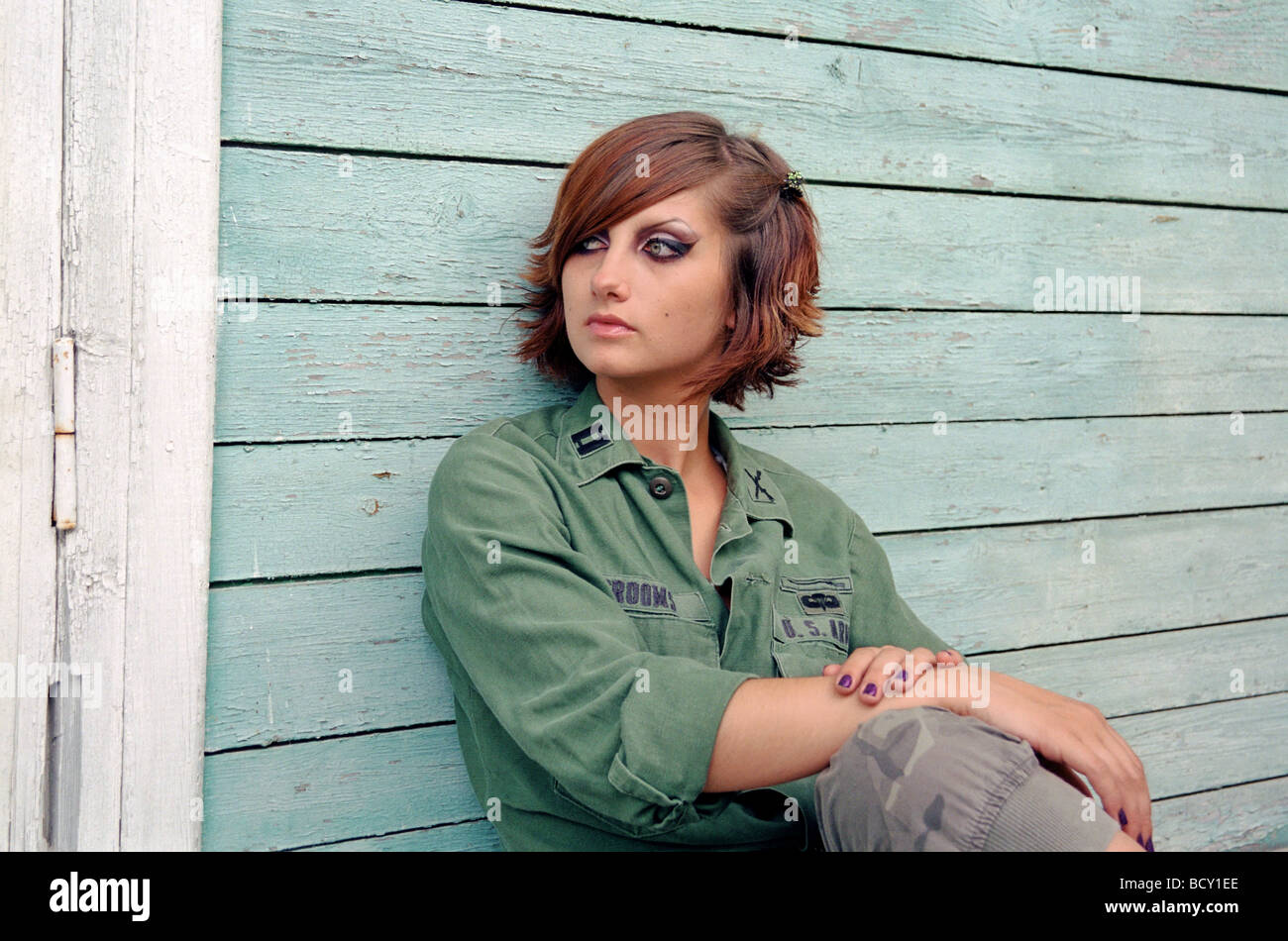 military woman sitting before wooden wall Stock Photo
