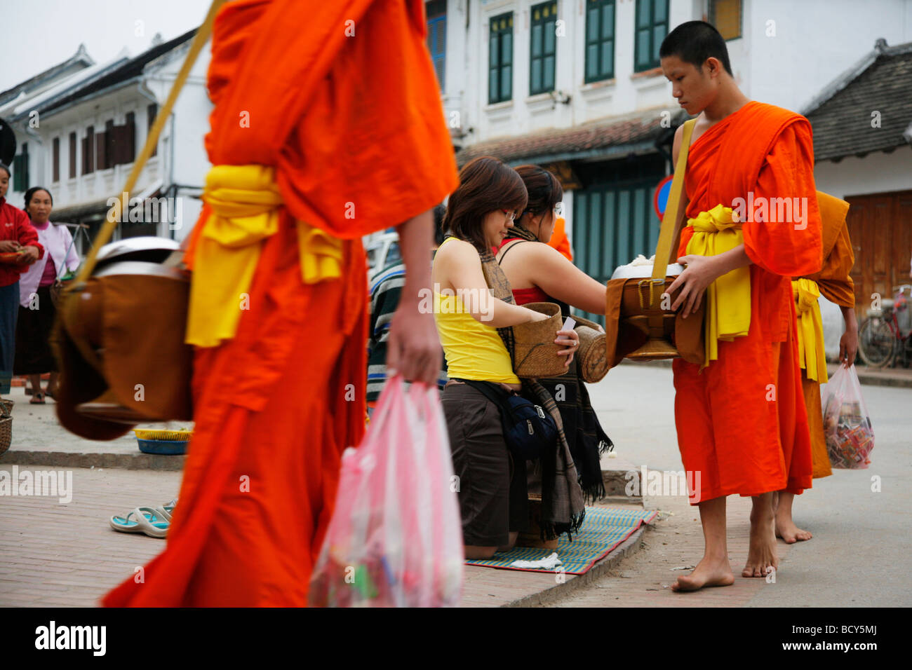 Monks receiving food donations at dawn in Luang Prabang in Laos Stock Photo