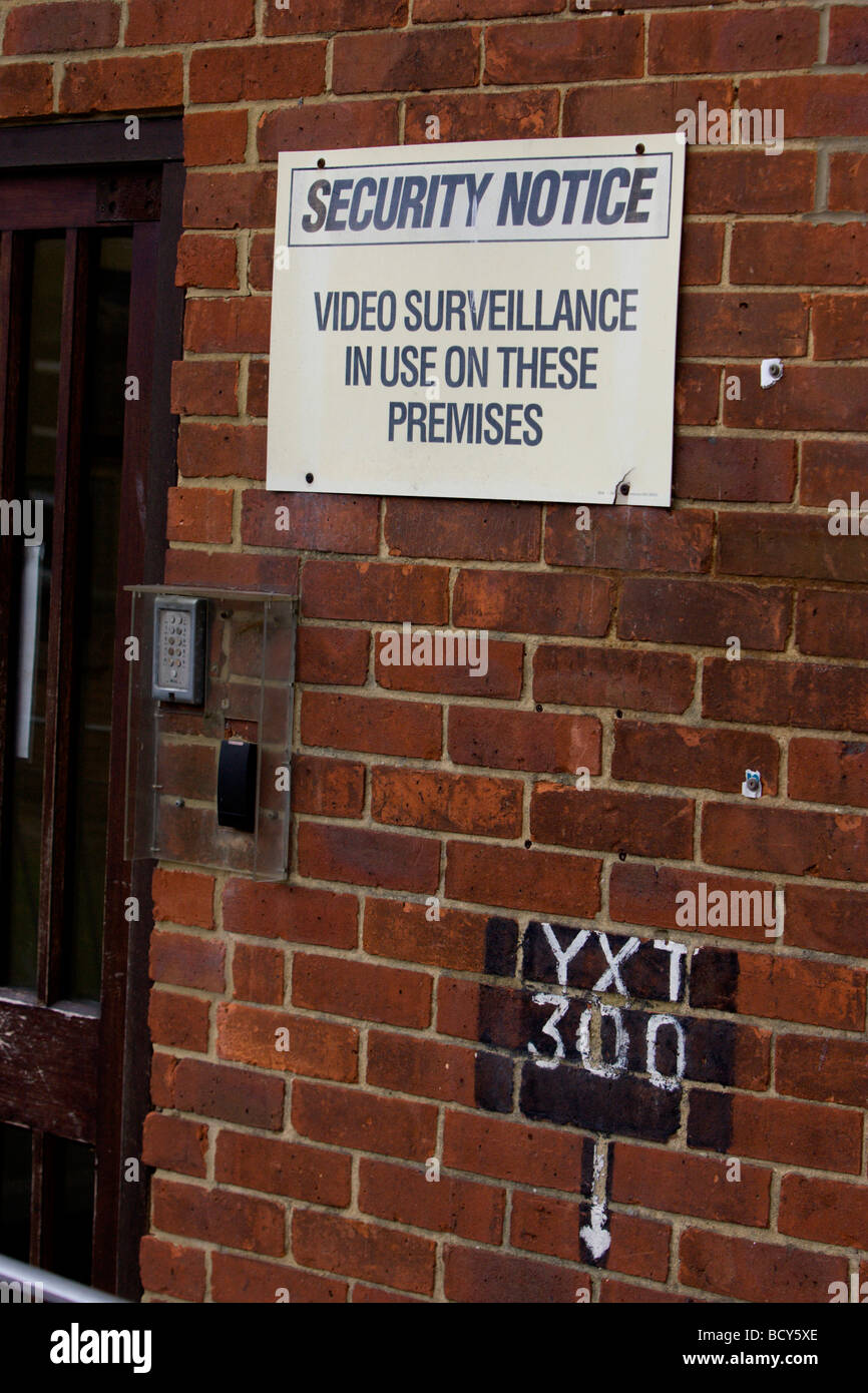 Brown wooden office security door with a yelloe sign warning of video surveillance, Brighton, East Sussex. Stock Photo