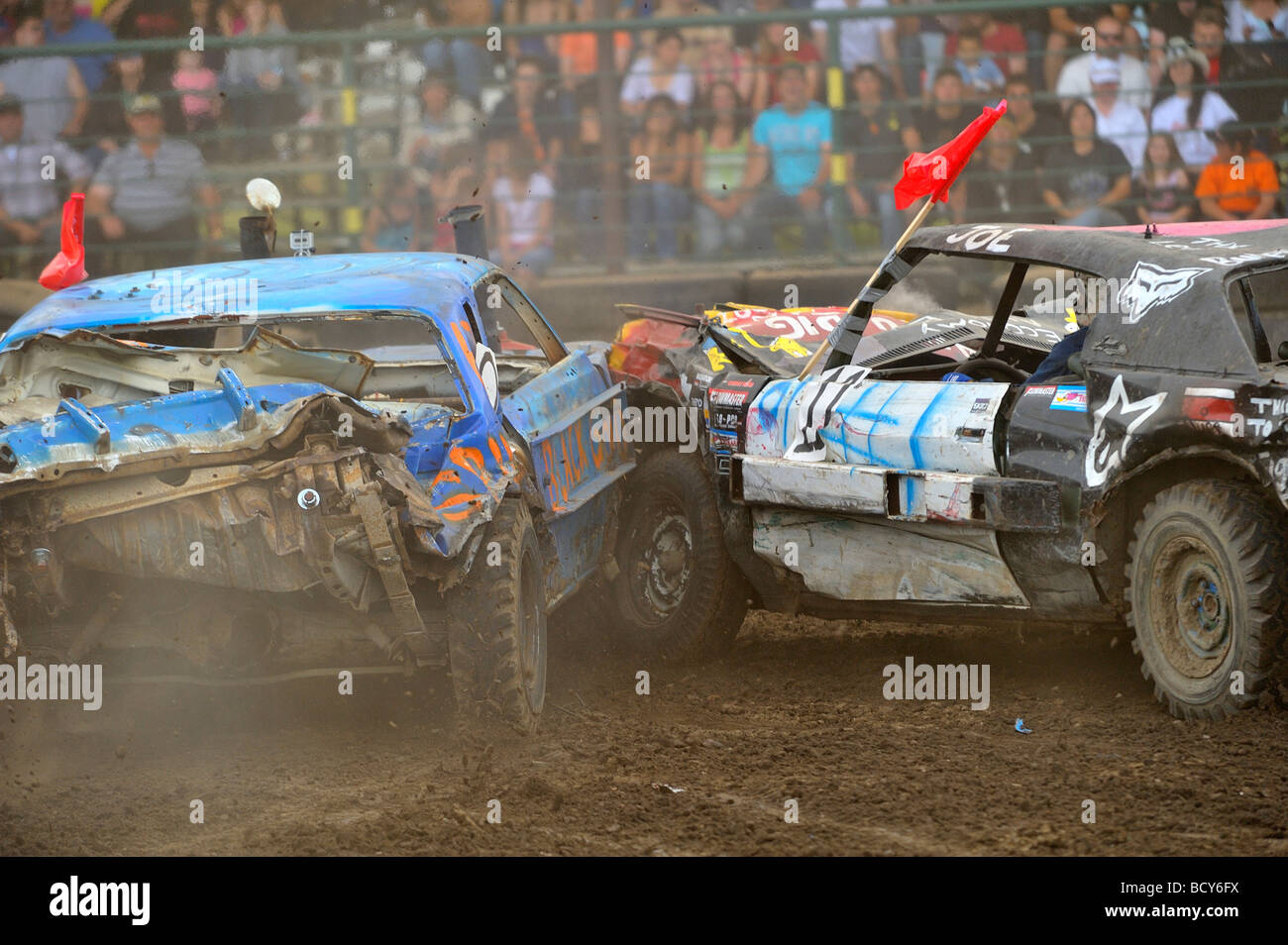 A large crowd of spectators watch as automobiles battle at a demolition derby Stock Photo