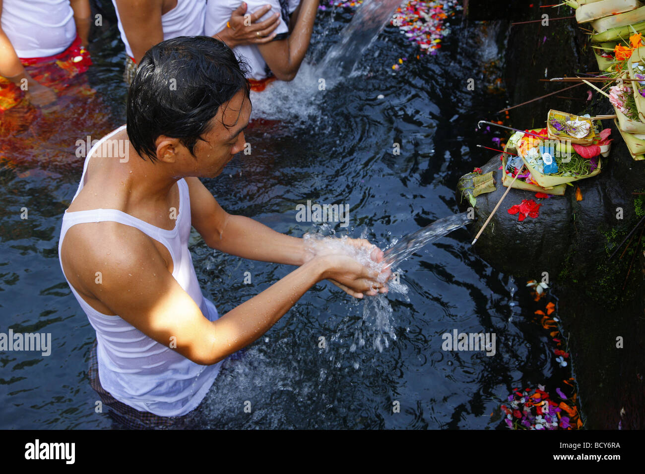 Man at a ceremony at a sacred spring, Tirta Empul at Tampak Siring in the morning light, Bali, Republic of Indonesia, Southeast Stock Photo