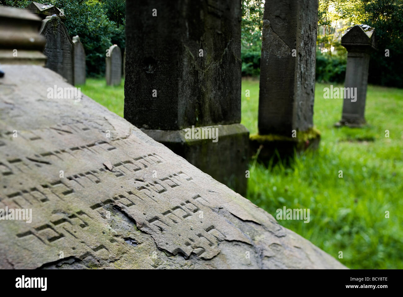 abandoned jewish cemetery, Essen-Kettwig, Germany, tilted tombstone with hebrew inscription in foreground Stock Photo