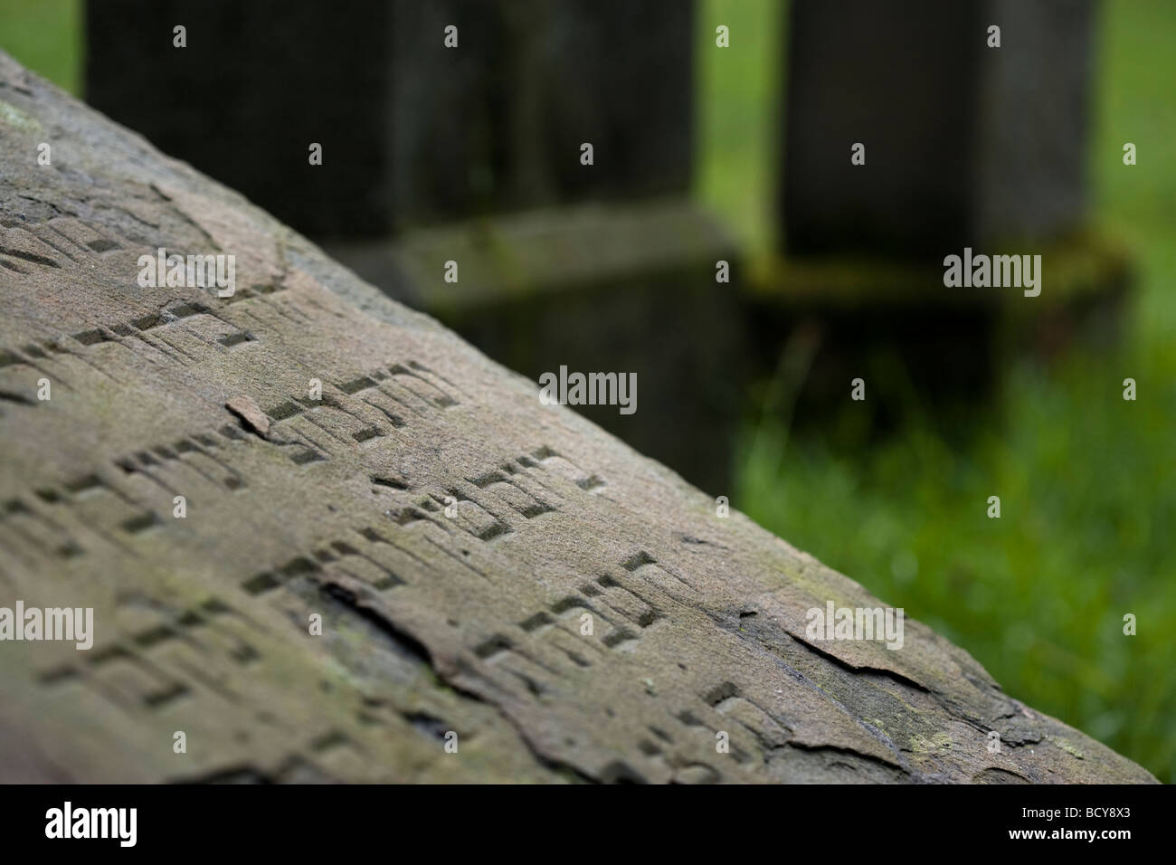 broken hebrew inscription on tilted tombstone at abandoned jewish cemetery, Essen-Kettwig, Germany Stock Photo