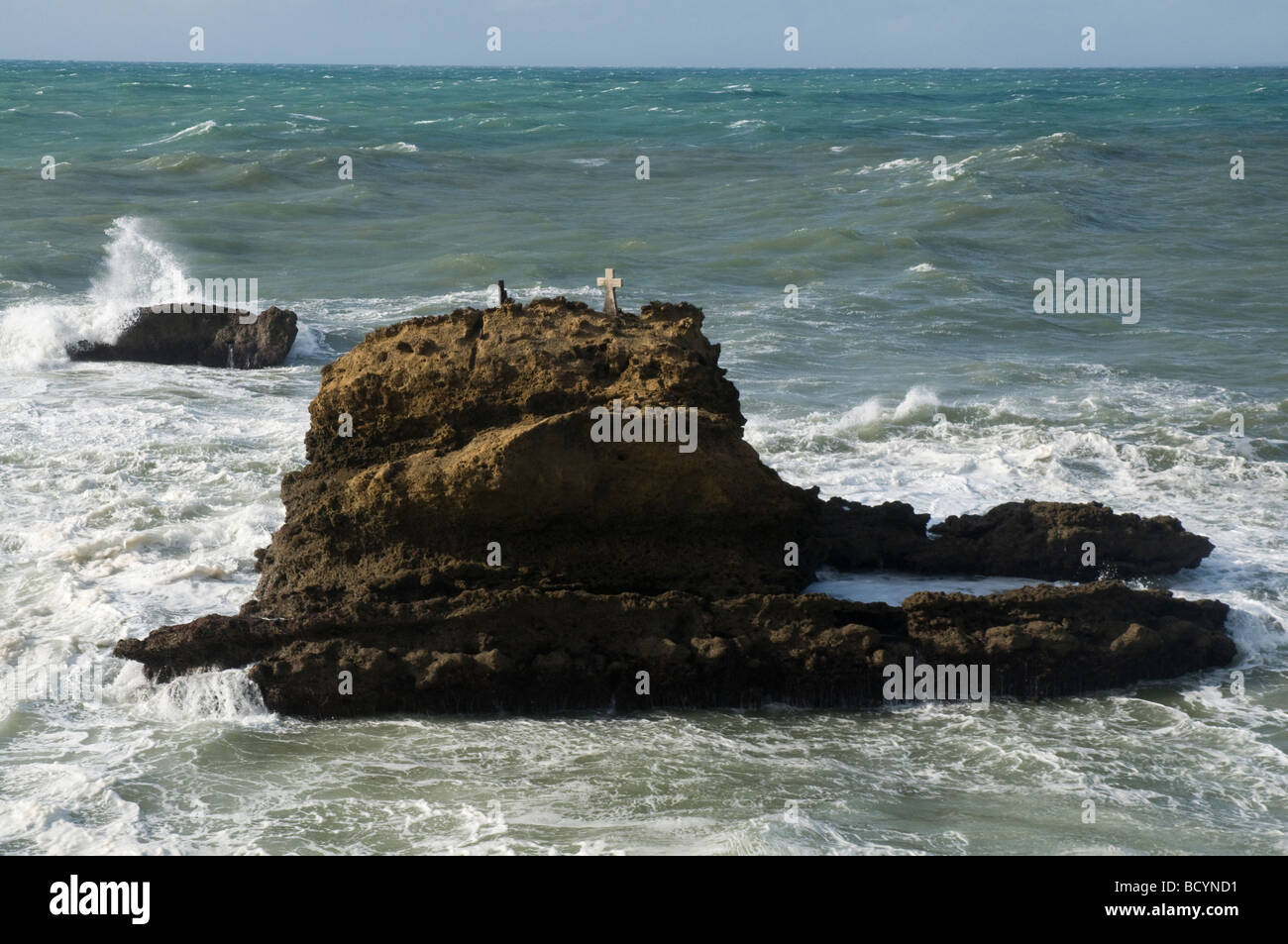 a rock in the sea, surmounted by a cross in memory to fishermen lost at sea Stock Photo