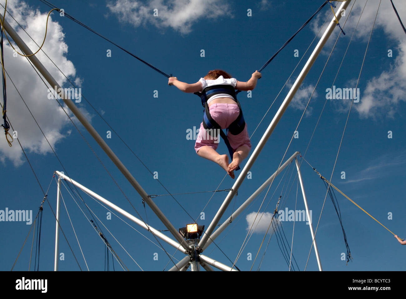 A red haired girl enjoys a trampoline ride under blue skies at the 5th Colchester Military Festival in Colchester, Essex, UK Stock Photo