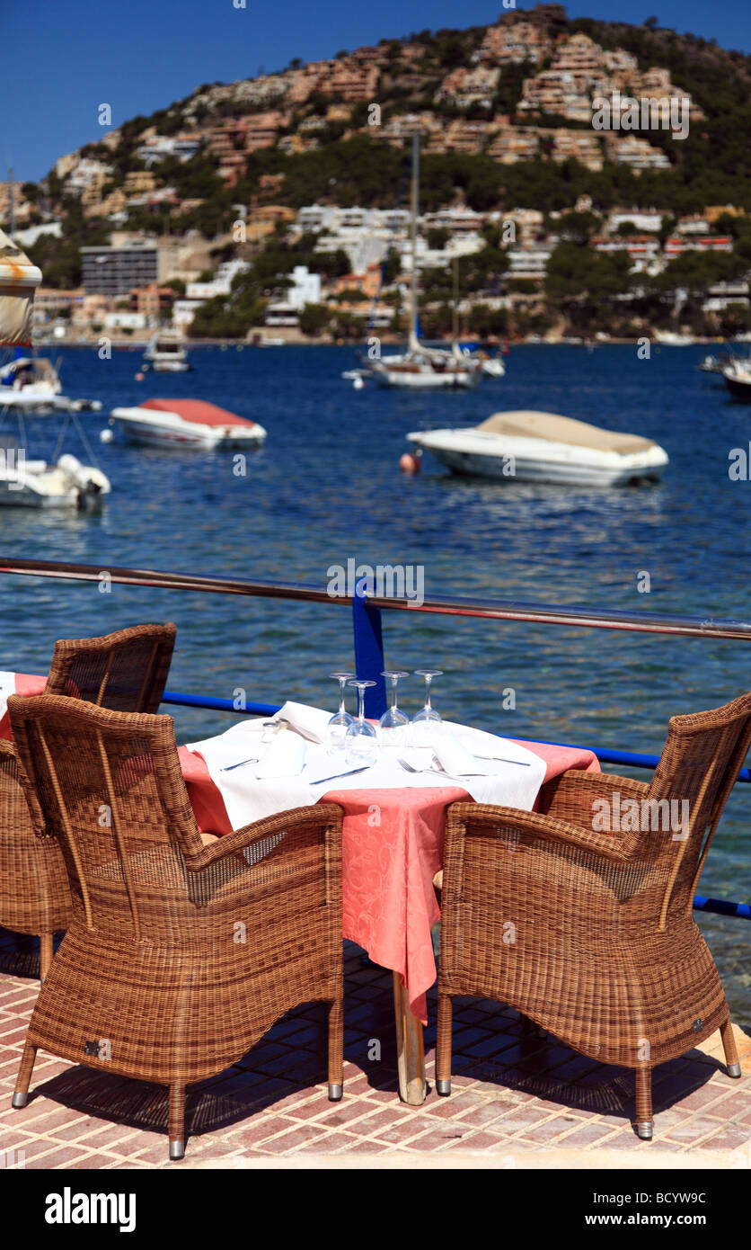 A restaurant table next to the sea on a harbour wall Stock Photo