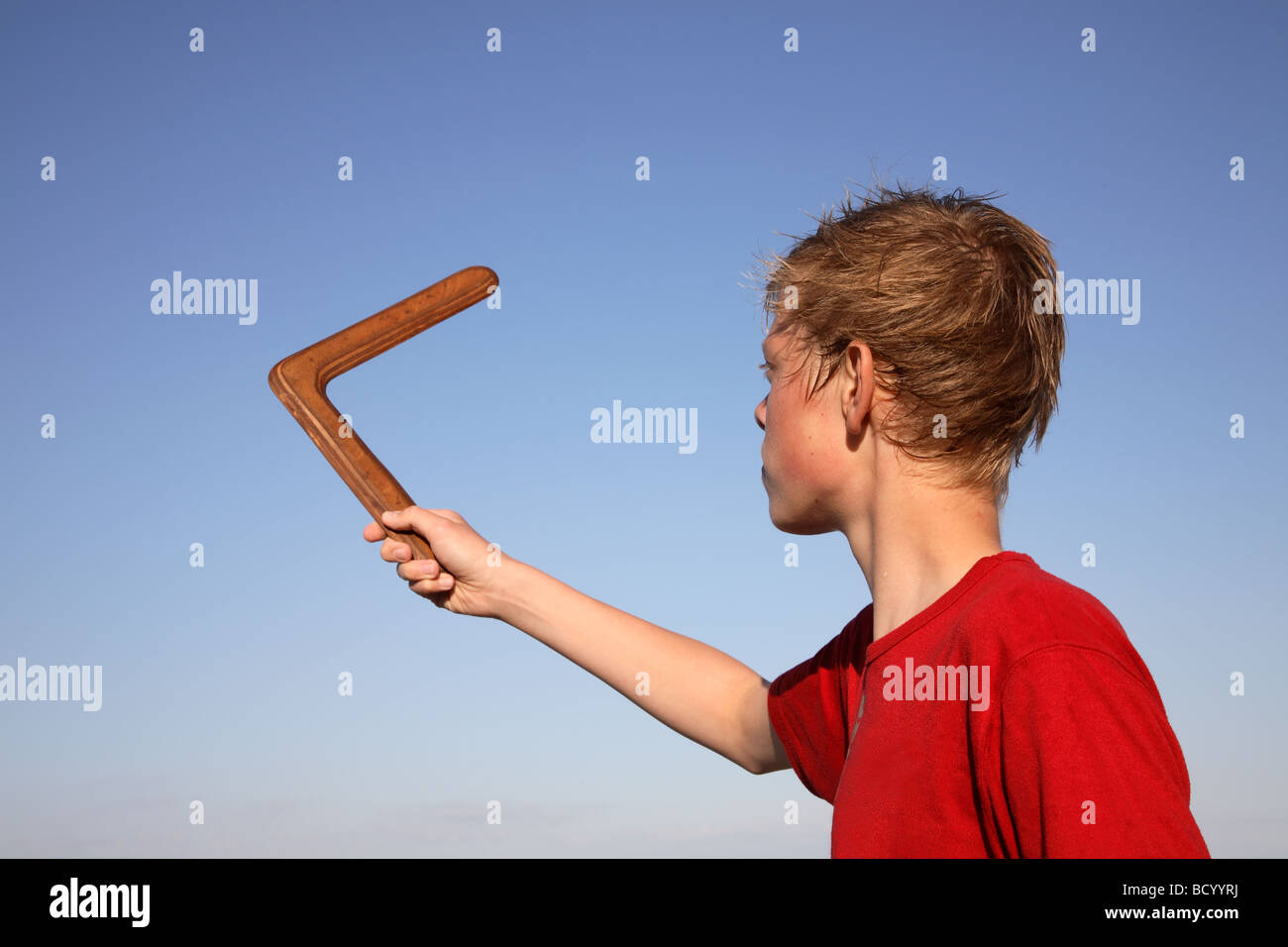 older teenage boy ready to throw a returning boomerang on the beach BCYYRJ