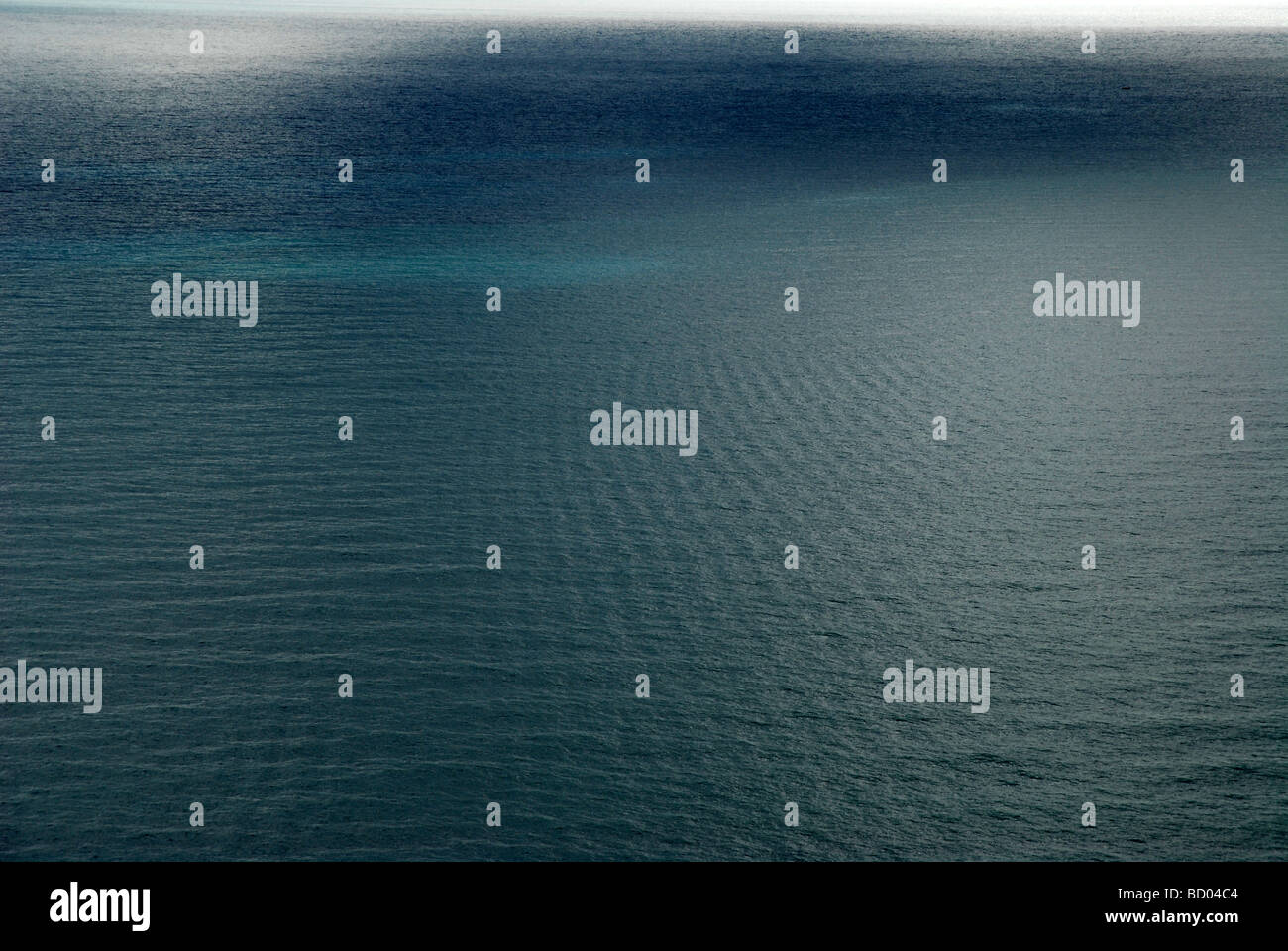 high angle view of large expanse of calm blue sea, with ripples and sunlight reflecting on water