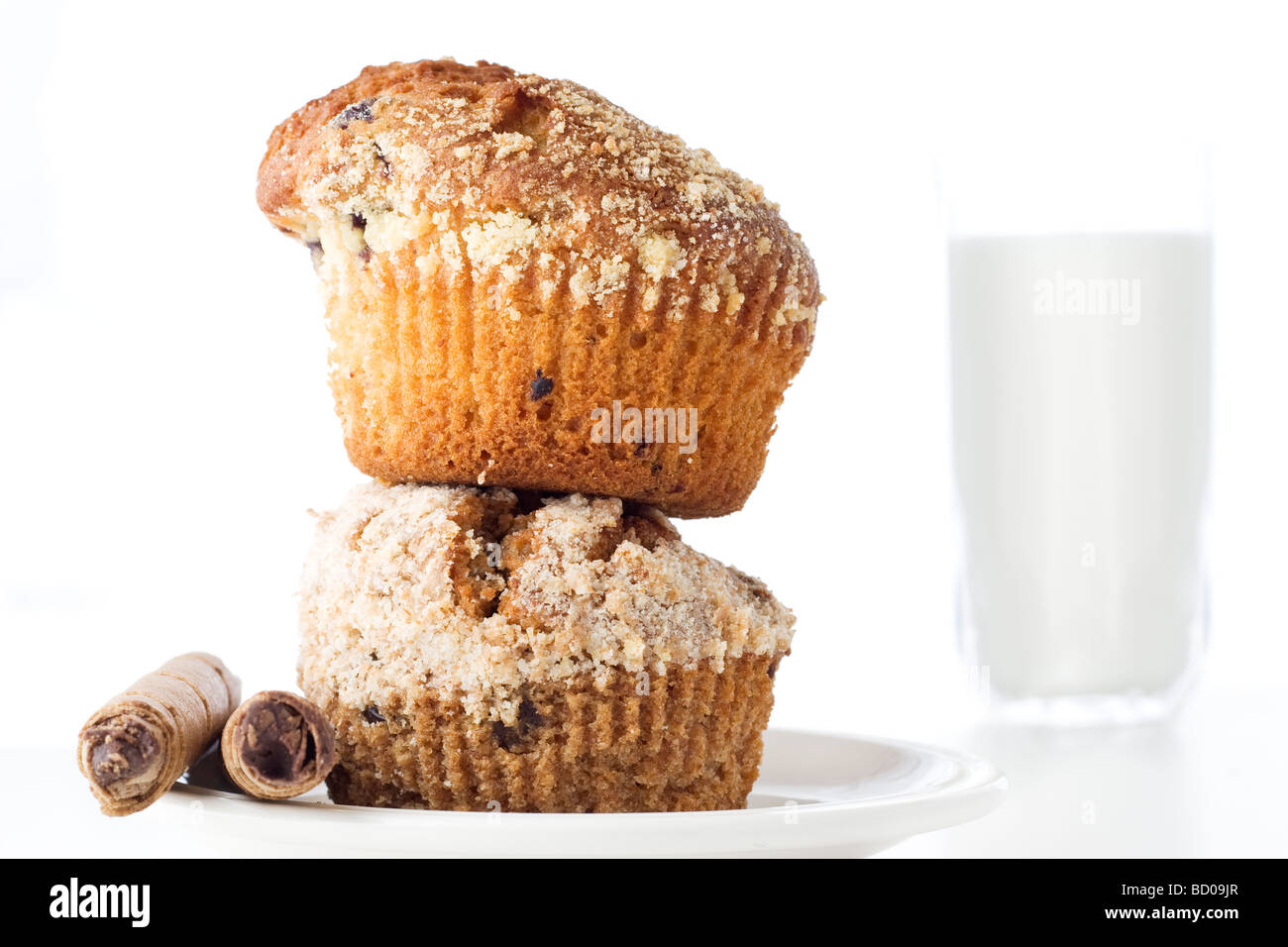 Two muffins one over another in white plate with a glass of milk in the background Stock Photo
