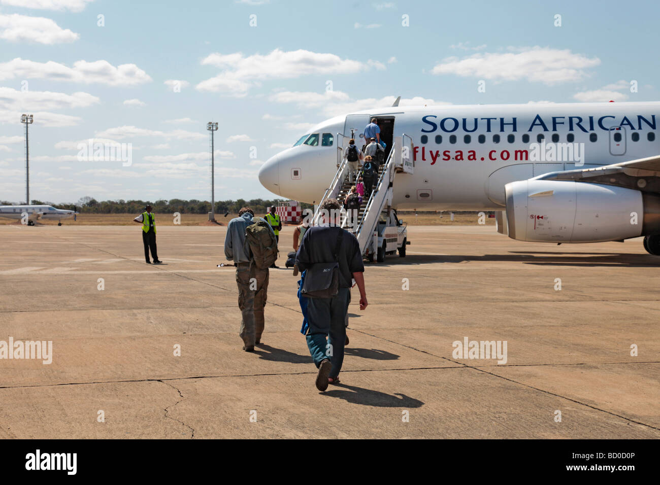Passengers walking towards an SAA jet aeroplane at Livingstone Airport, Zambia (now called Harry Mwanga Nkumbula Airport) Stock Photo