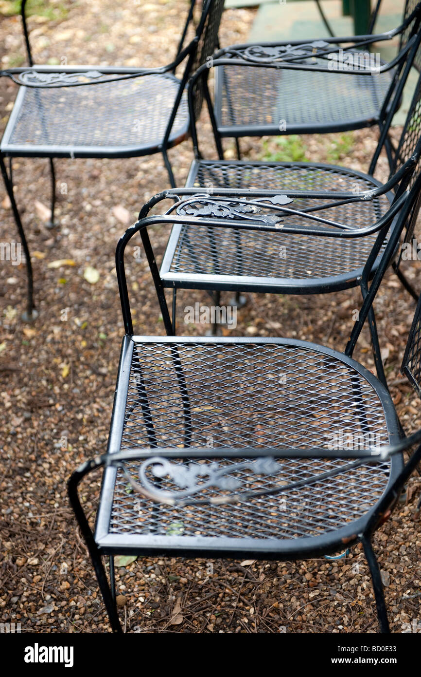 Black metal chairs on gravel path with decorative armrests Stock Photo