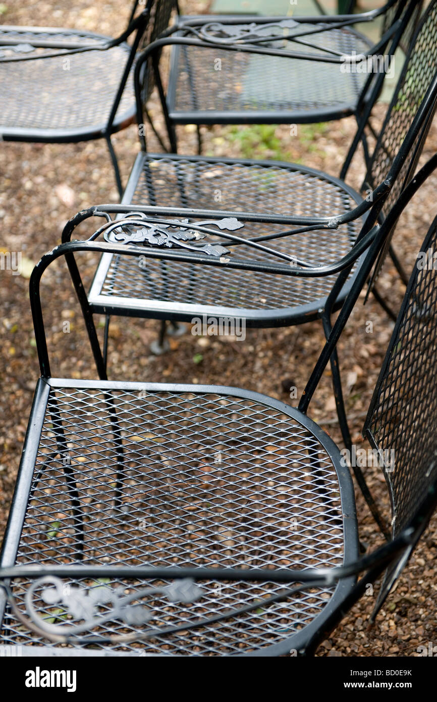 Black metal chairs on gravel path with decorative armrests Stock Photo