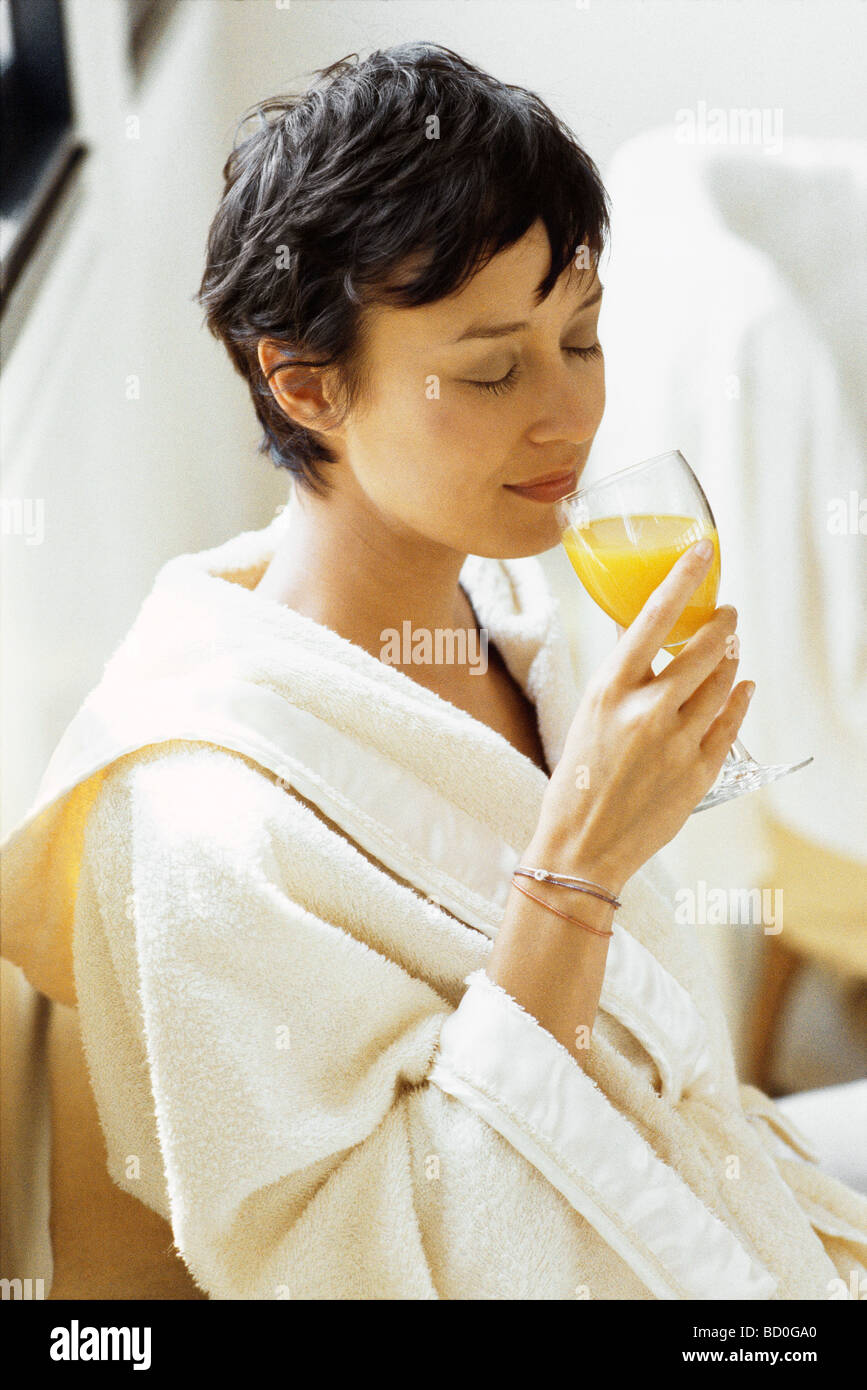 Woman in bathrobe drinking orange juice Stock Photo