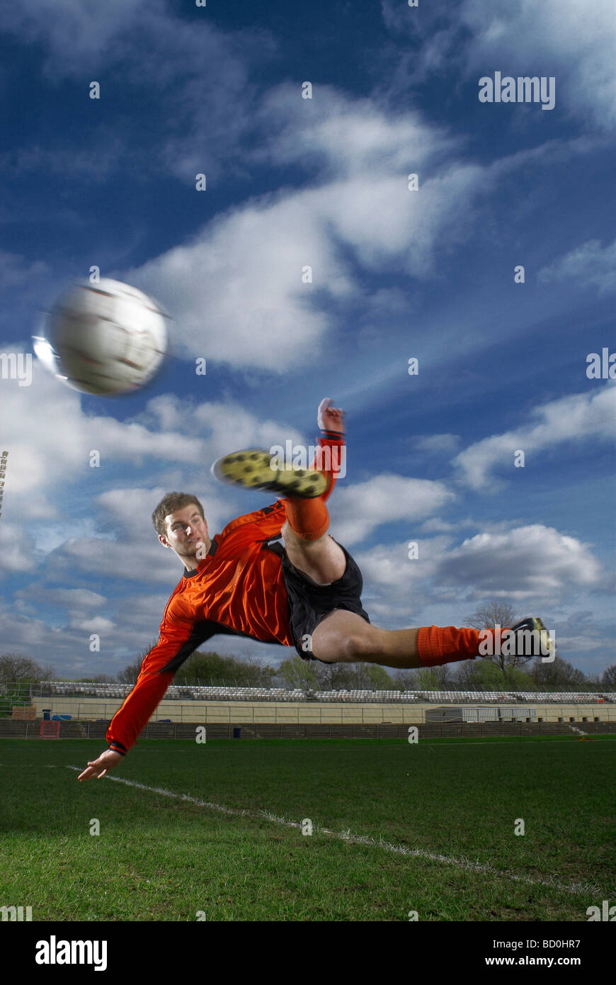 footballer volleying ball mid air Stock Photo