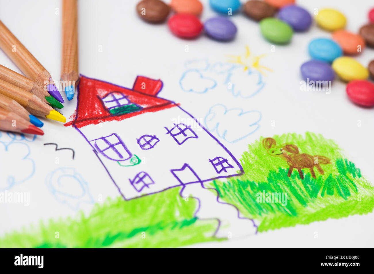 Child's drawing of a house and pet dog with coloured pencils surrounded by smarties Stock Photo