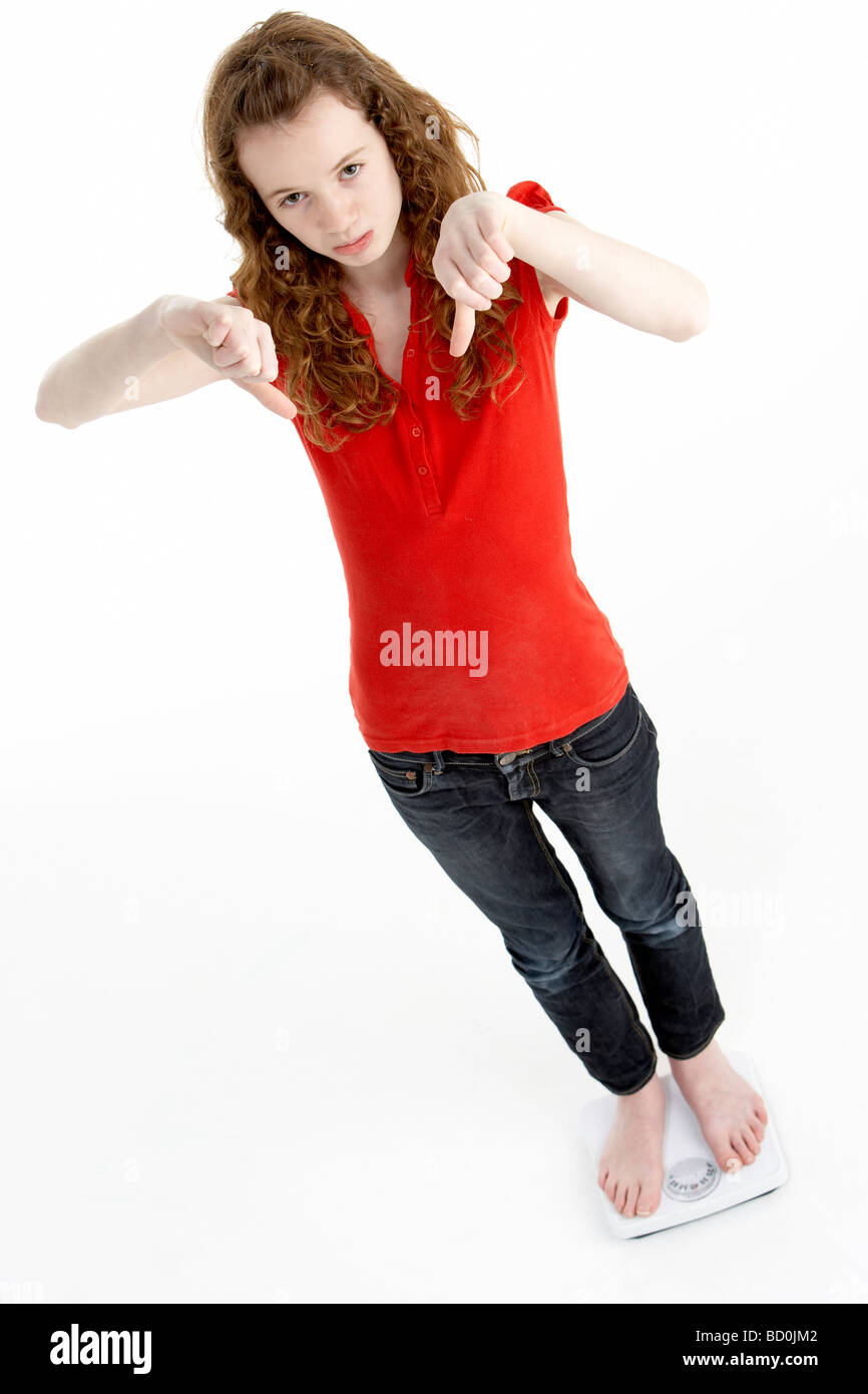 Unhappy Young Girl Standing On Scales Stock Photo