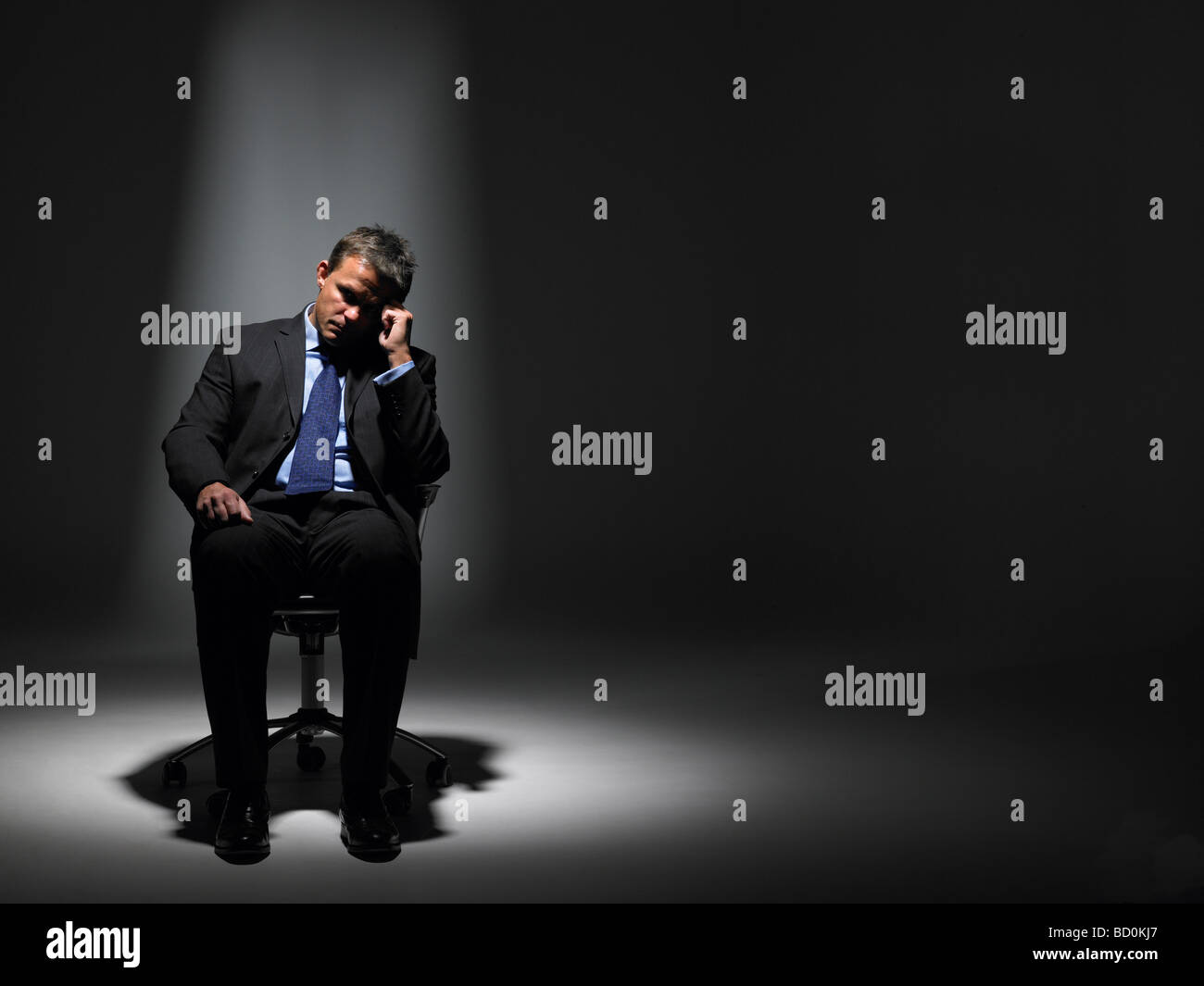 Businessman Sitting In Spotlight Stock Photo