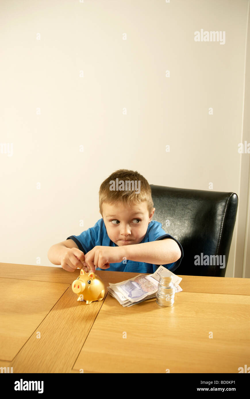 boy putting money in piggy bank Stock Photo - Alamy