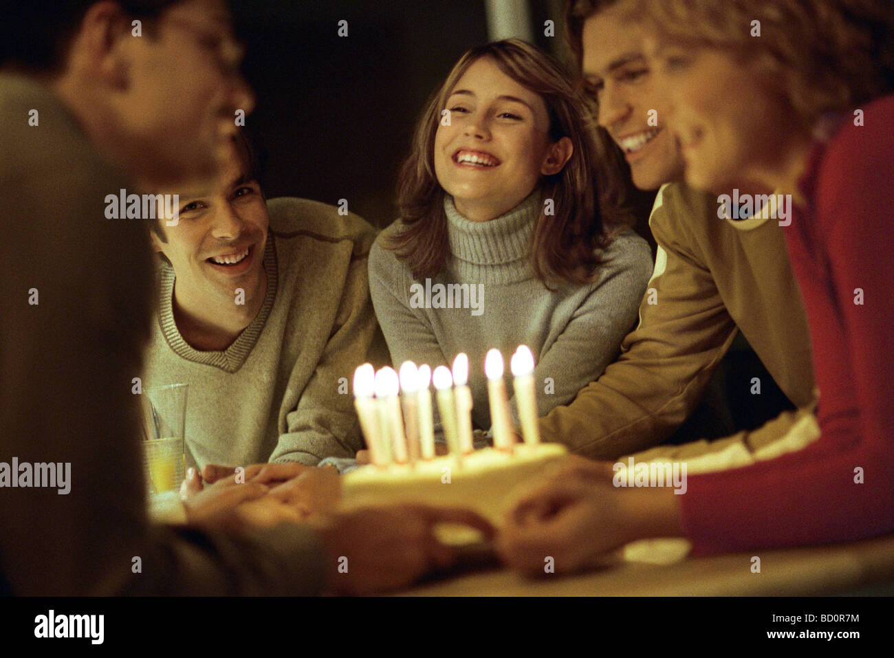 Friends gathered together presenting birthday cake to friend Stock Photo