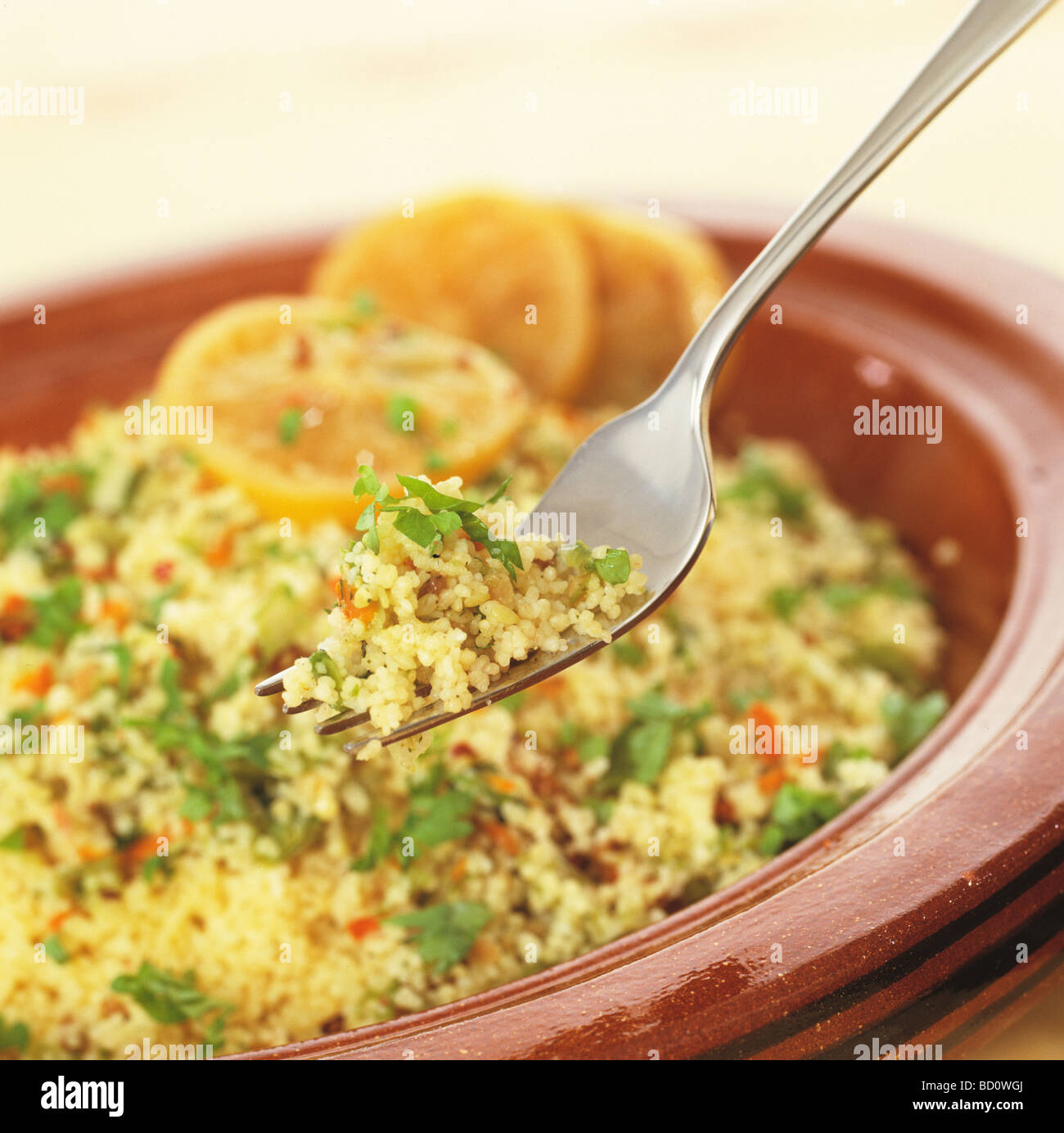 couscous and herbs in bowl with orange slices Stock Photo