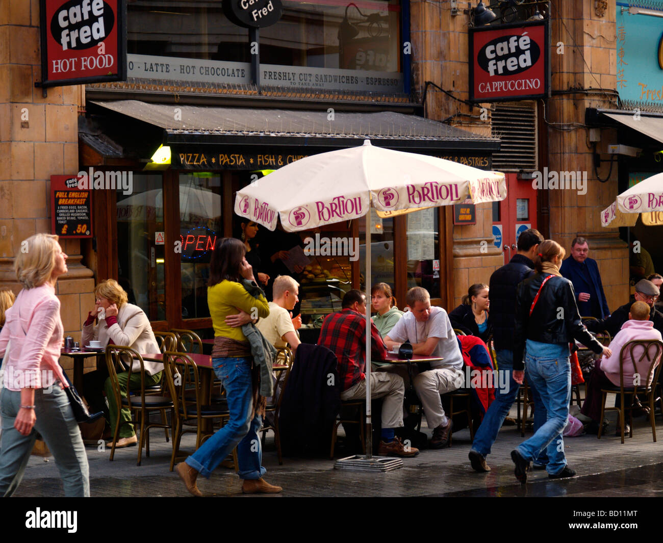 People sitting at a pavement cafe with passers by in a sidestreet of Oxford Street shopping district London UK Stock Photo