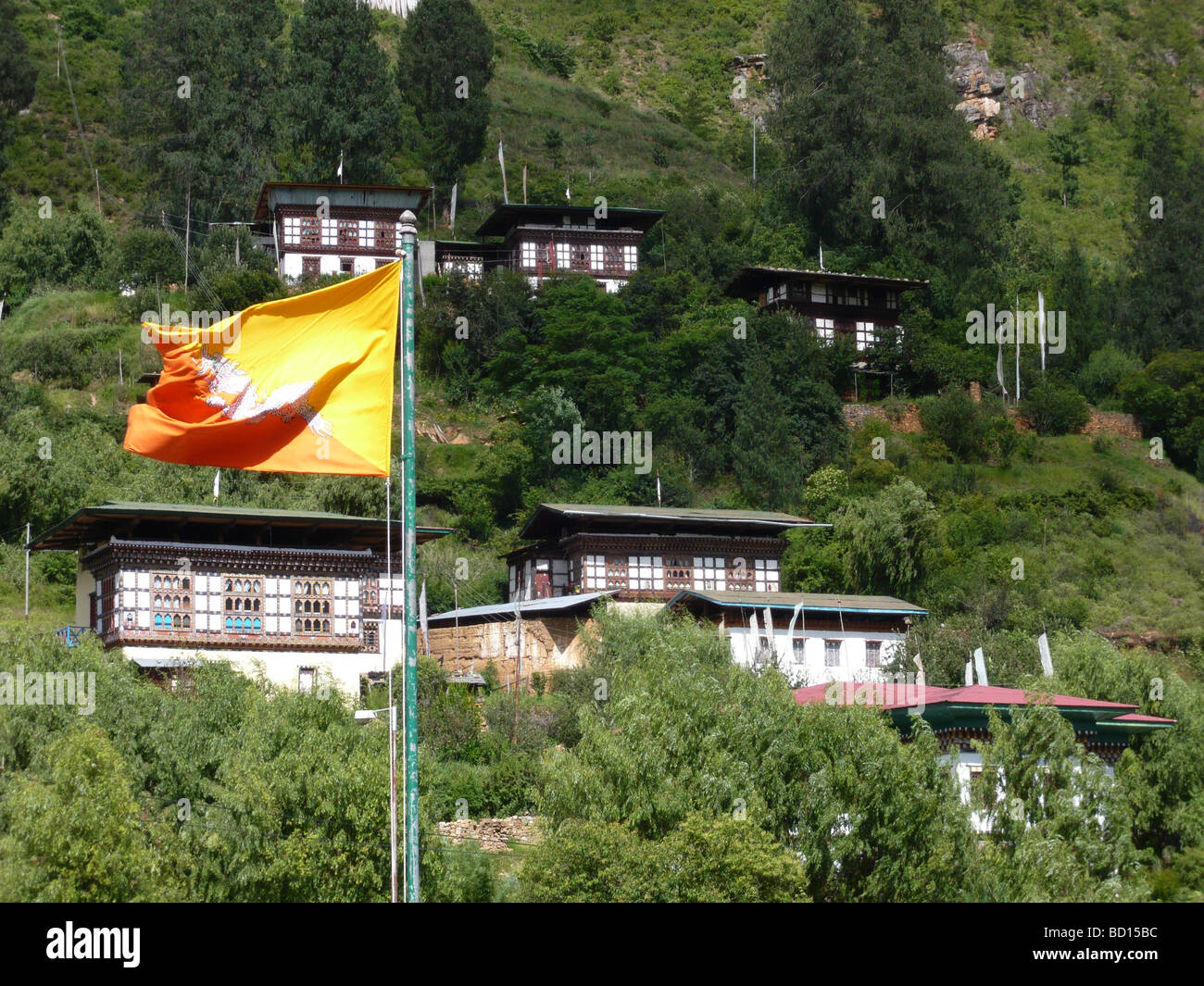 National flag of Bhutan with typical houses in the back above the Dzong of Paro Stock Photo