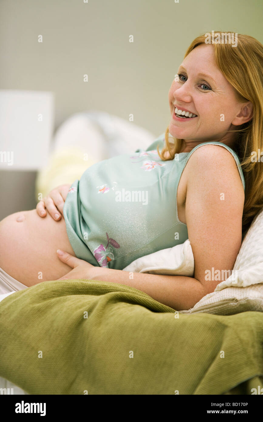 Pregnant woman reclining, hands on bare belly, smiling Stock Photo Alamy