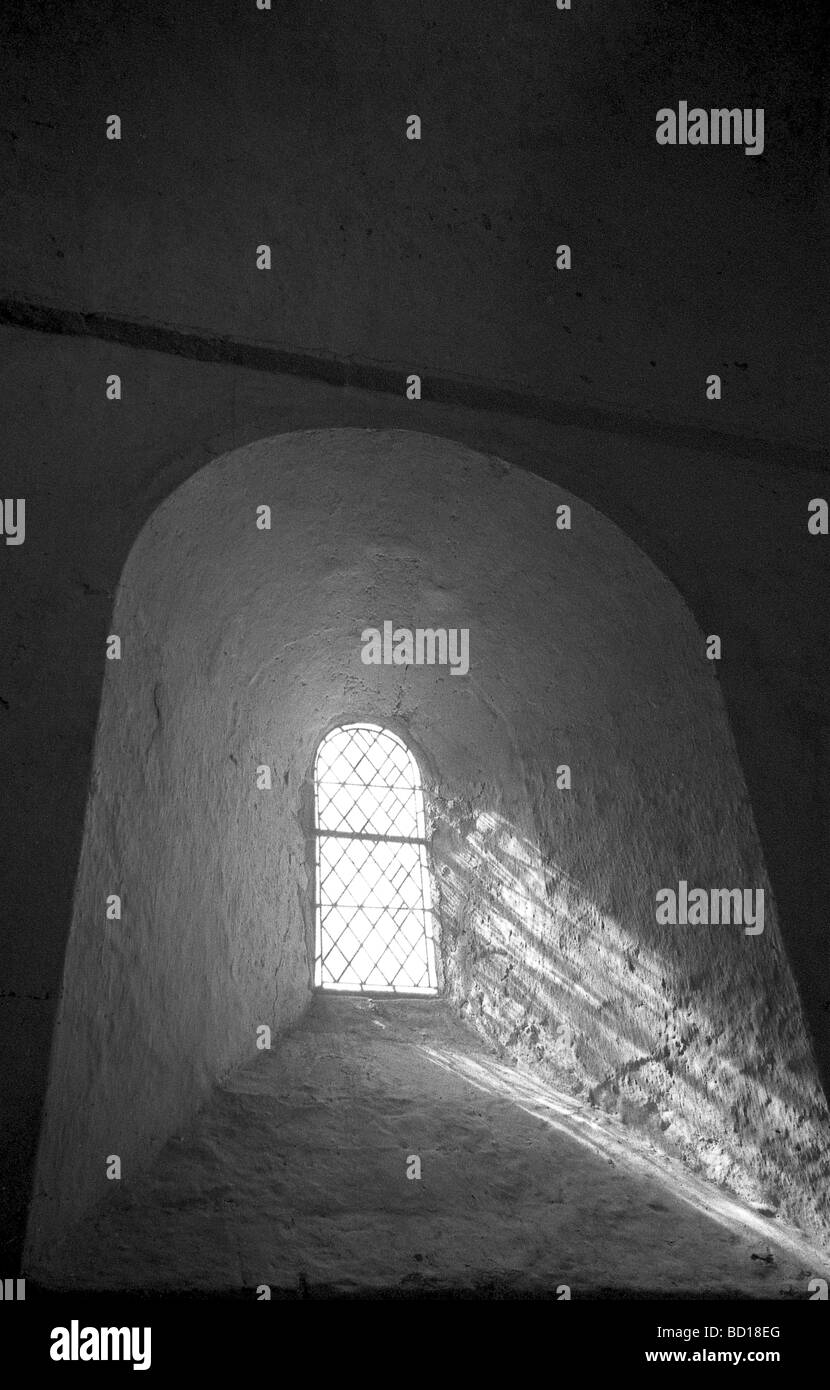 medieval window with sun shining through lead light in black and white Stock Photo