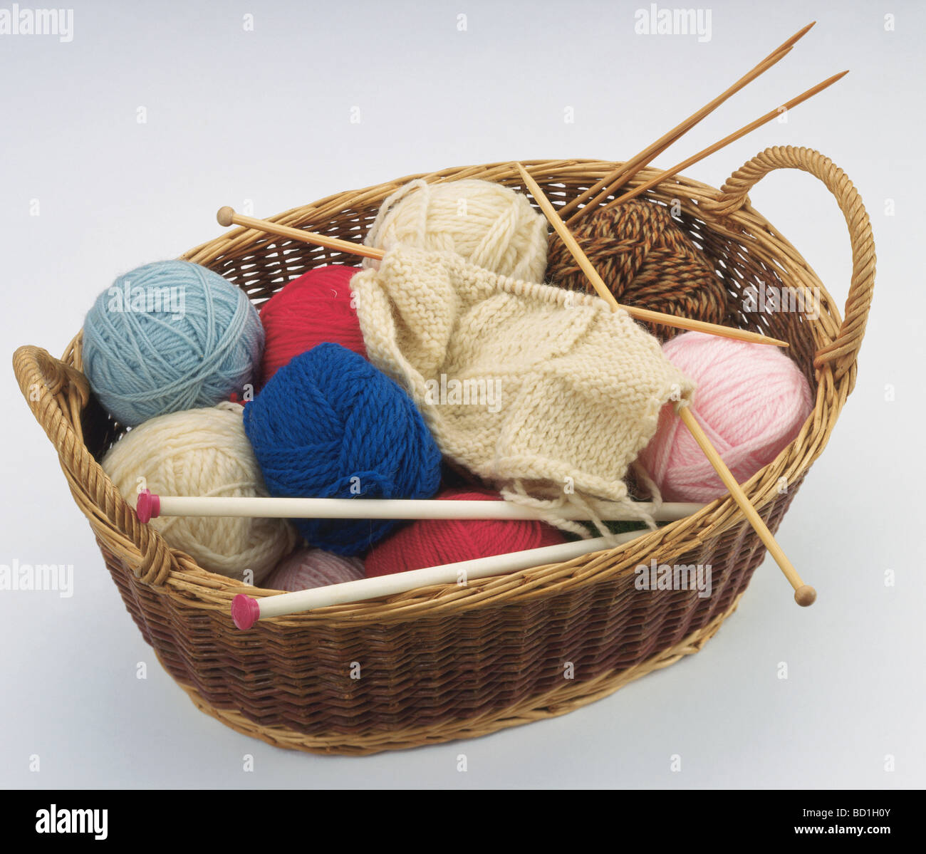 Knitting needles and yarn balls in basket white background Stock Photo ...