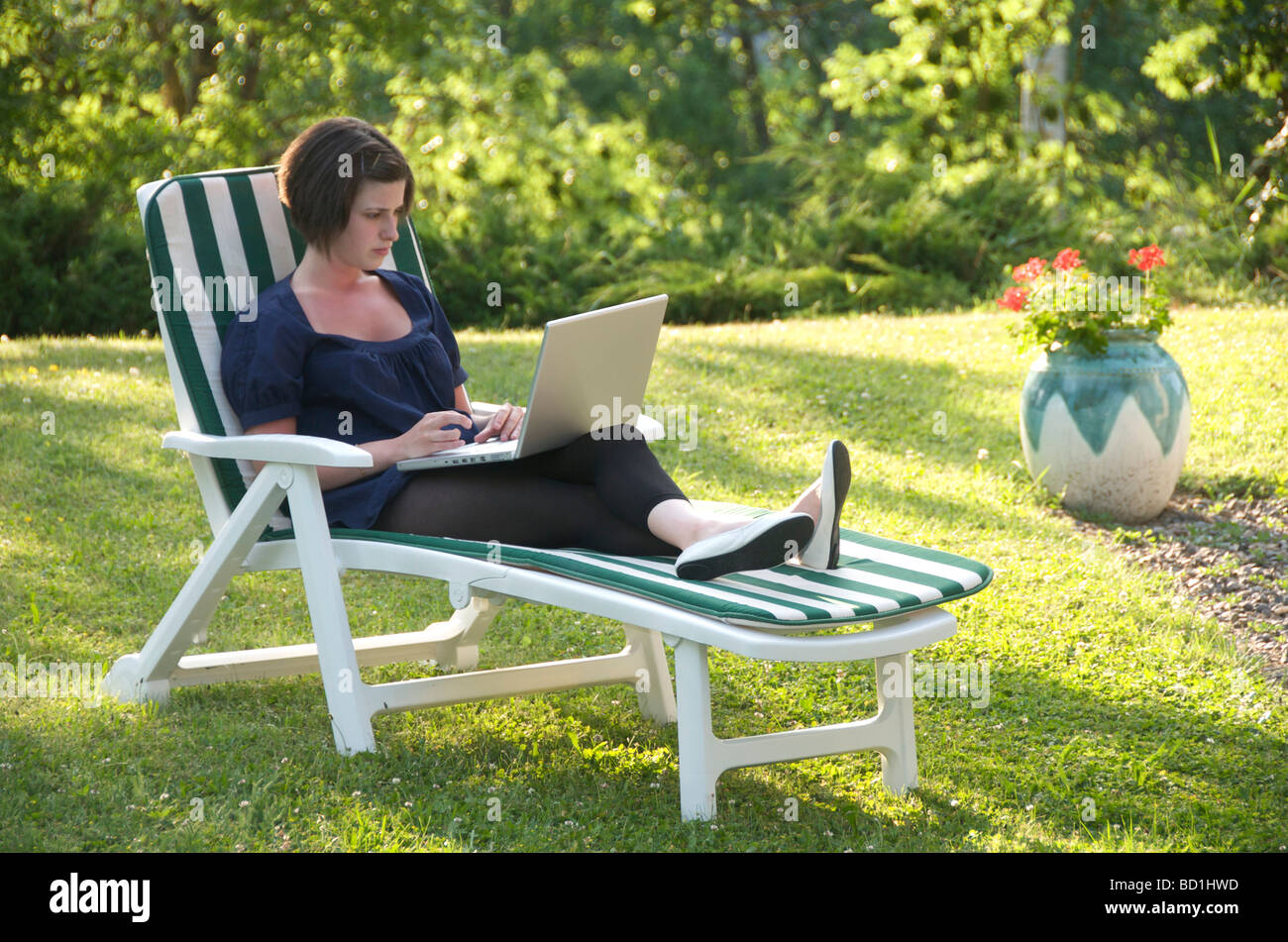 Young woman / teenager with laptop computer sitting in the garden. Stock Photo