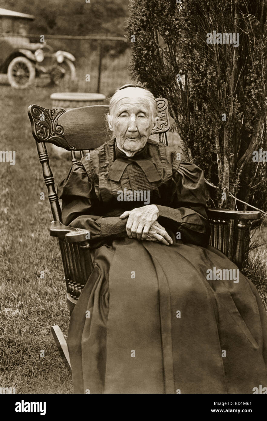 Ancient Woman Seated in Rocking Chair Outdoors Stock Photo