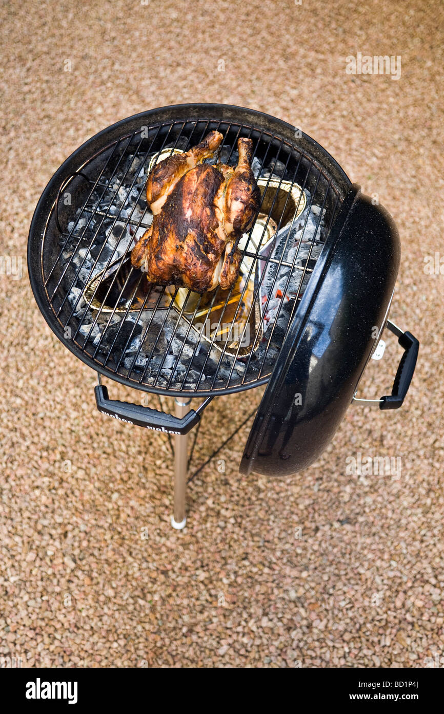 The roasting of a free-range chicken thanks to a barbecue set. Cuisson d un poulet fermier dans un barbecue à couvercle. Stock Photo