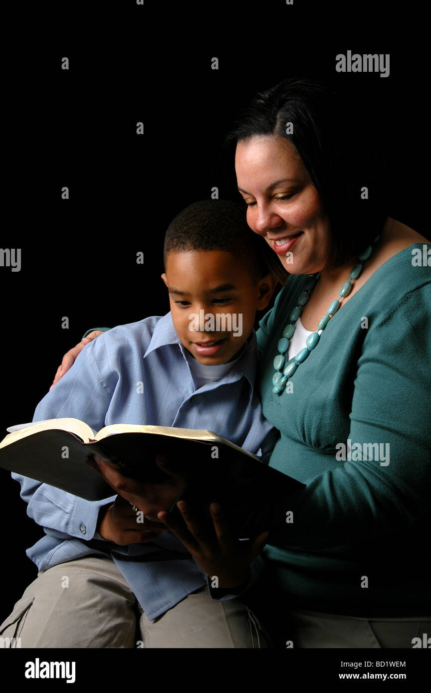 African American mother and son reading Bible over a black background Stock Photo