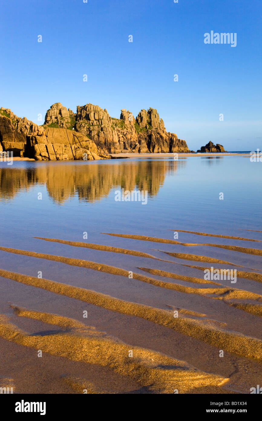 reflections at sunset Pednvounder beach near porthcurno with Logan Rock in distance cornwall Stock Photo