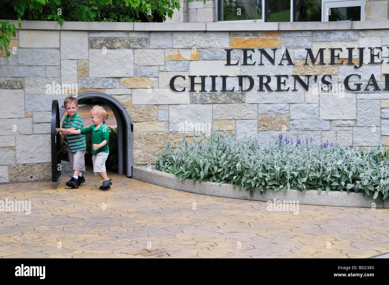 Children walk through the miniature gate at the Lena Meijer Childrens Garden part of the Frederik Meijer Gardens Sculpture Park Stock Photo