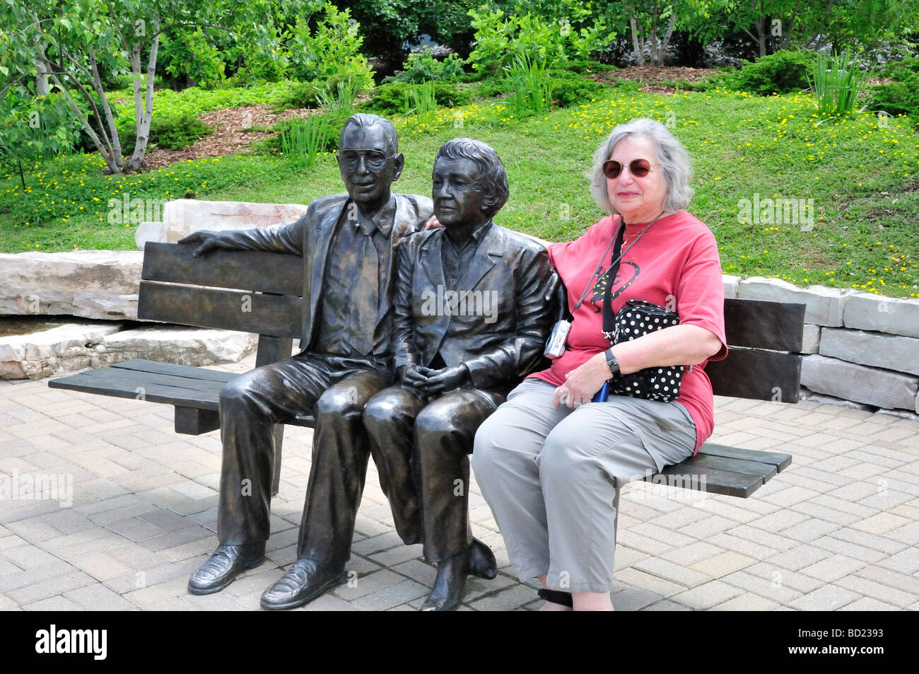 A visitor joins bronze statues of Frederick and Lena Meijer at the Frederik Meijer Gardens Sculpture Park Stock Photo