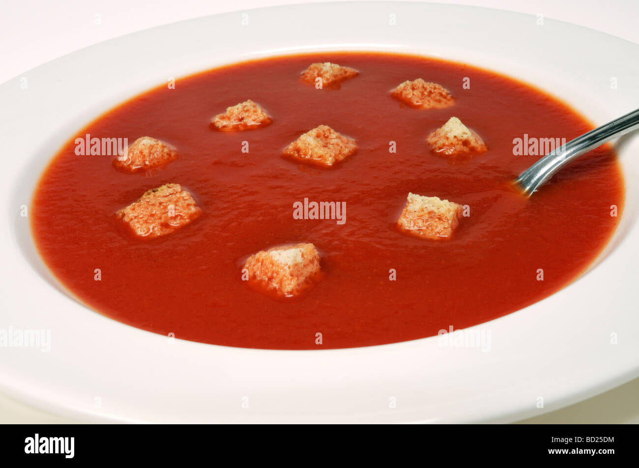 Close up of bowl of tomato soup in white bowl with croutons on white background. Stock Photo