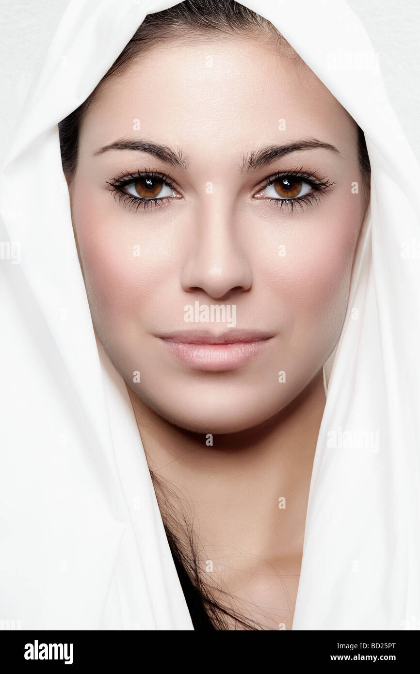 Portrait of a young woman wrapped in white cloth, looking directly towards the camera Stock Photo