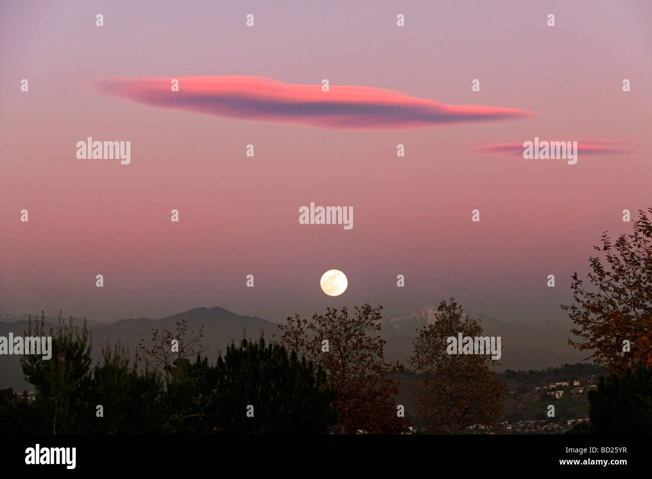 Full moon rise at sunset over San Gabriel valley hills top, cover with winter snow. Stock Photo