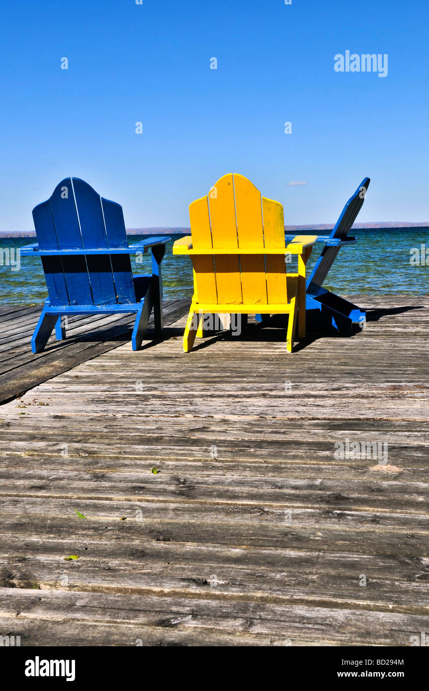 Painted wooden chairs on dock at a lake Stock Photo - Alamy