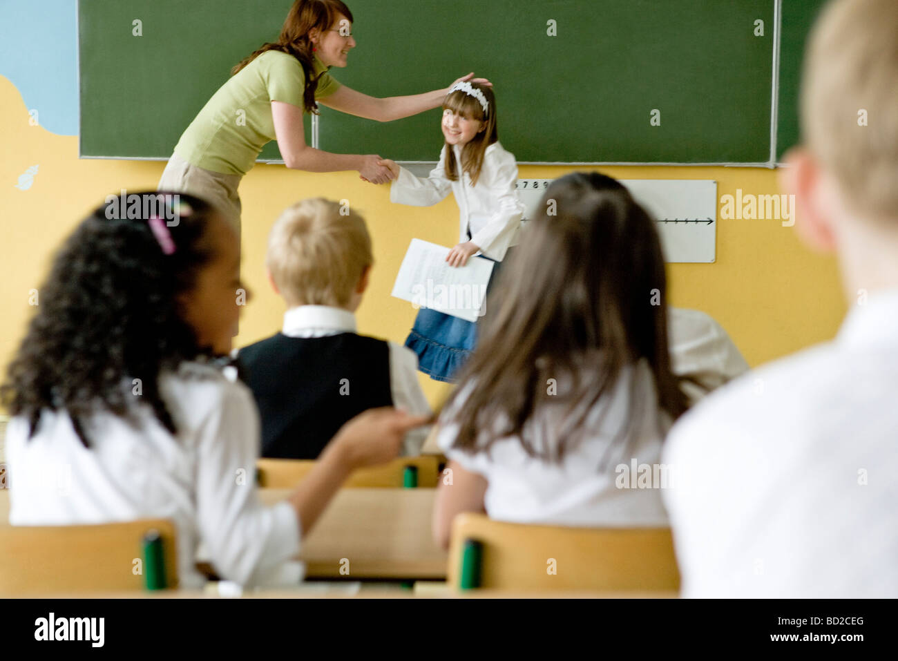 Teacher giving school reports to children Stock Photo